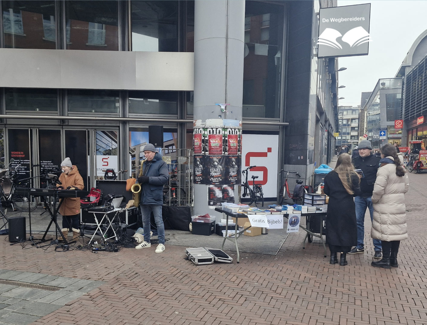 Een meisje speelt keyboard naast een saxofonist tijdens evangelisatie op straat